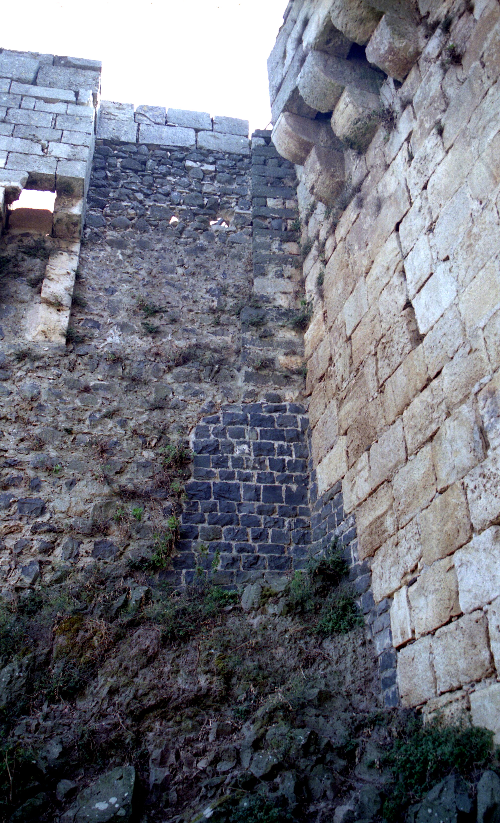 Secteur 7. Angle rentrant du saillant 32 avec l'ouvrage de la poterne nord. A gauche, départ de la courtine franque du saillant 32 ; elle se raccorde à un élément de mur de basalte en appareil régulier qui constitue l'angle de l'ancienne enceinte de la basse-cour nord-est A droite, mur de l'ouvrage de la poterne nord (cl. JM 95).